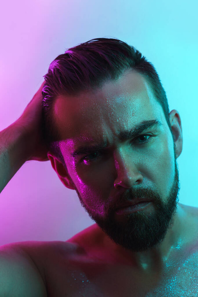 Portrait of handsome young man with wet skin in neon light - Foto, Imagem