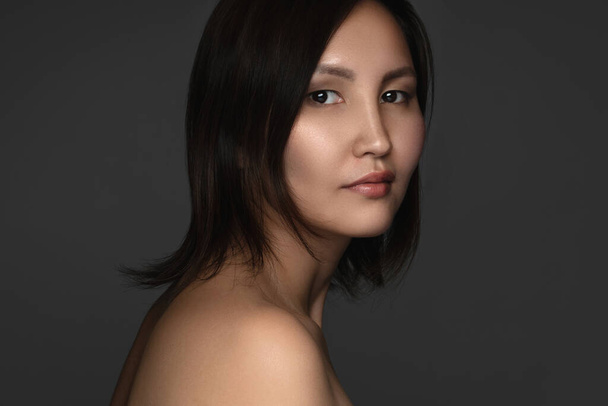 Porträt einer jungen und schönen asiatischen Frau auf grauem Hintergrund - Foto, Bild