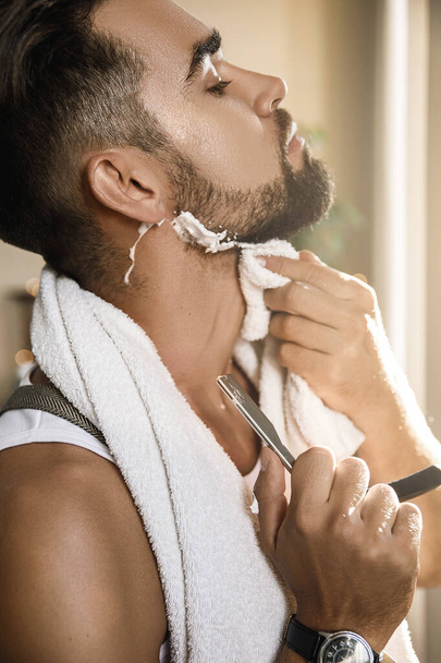 Handsome man shaving his beard with a straight razor - Фото, изображение