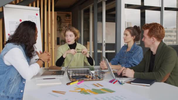Střední záběr veselá mladá podnikatelka sedí u stolu v zasedací místnosti moderní start-up firemní kanceláře a sdílení nápadů na projekt se svými kolegy - Záběry, video