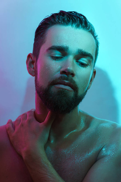 Portrait of handsome young man with wet skin in neon light - Zdjęcie, obraz