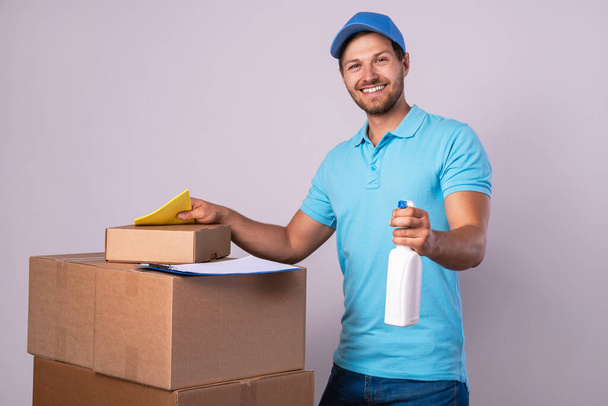 Happy delivery man during work with a packages in a cardboard boxes over gray background - Foto, Imagen