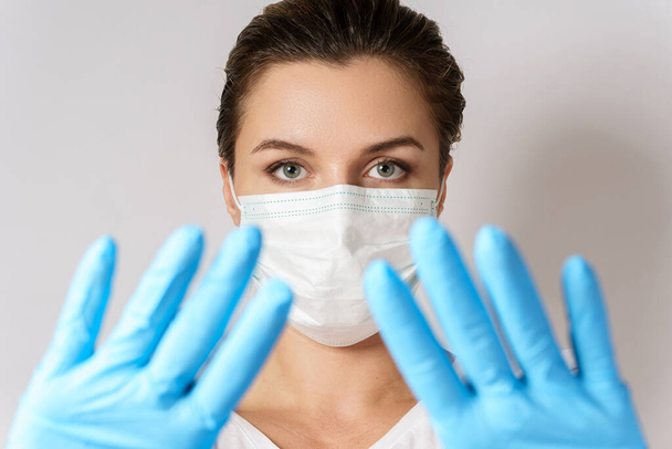 Молода біла жінка носить маску для обличчя і латексні рукавички для захисту від вірусу
 - Фото, зображення
