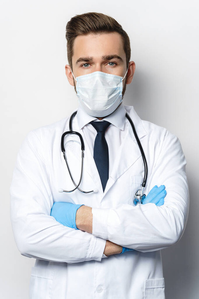 Confident doctor with the stethoscope wearing prevention mask and latex gloves - Fotó, kép