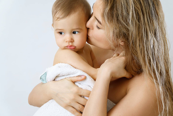 Baby hygiene and care. Young and happy mother and her cute infant son after bathing. - Zdjęcie, obraz