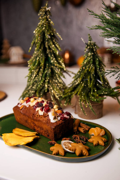 Christmas poppy seed cake covered with icing and decorated with raisins and walnuts on the holiday table. - Photo, image