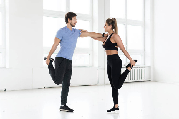 Fitness man and woman during workout with in the gym.  Quadriceps muscles warm-up. - Fotó, kép