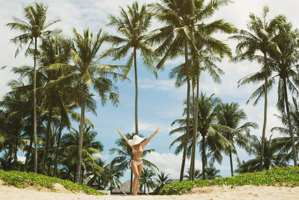 Piękna i szczęśliwa kobieta na plaży z palmami - Zdjęcie, obraz