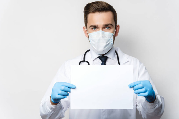 Confident doctor is holding a sheet of blank white paper - Zdjęcie, obraz