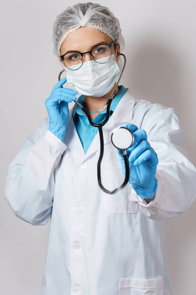 Young female doctor pulmonologist with a stethoscope on gray background - Fotó, kép
