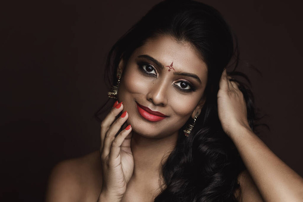 Portrait of Young Indian woman with beautiful makeup and hairstyle on brown background - Foto, Imagem