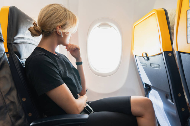 Young woman listening music inside an airplane during her flight - Φωτογραφία, εικόνα