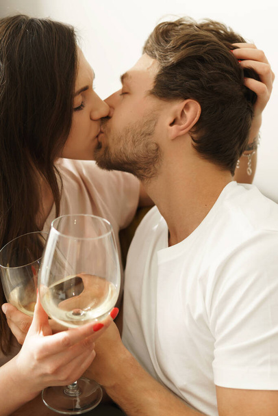 Young sensual couple drinking white wine and relaxing at home - Zdjęcie, obraz