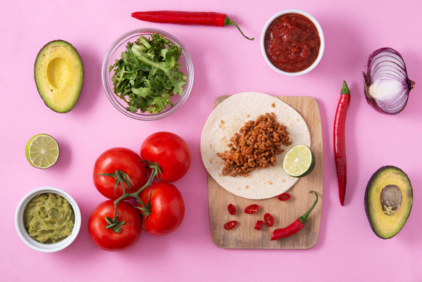 Mexican barquita taco ingredients with beef, chilli, tomato, onion and spices pattern on pink background - Photo, Image