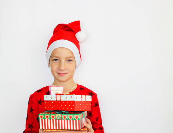 little Santa Elf boy is waiting for Christmas and presents on him a red sweater. He smiles and holds the presents in his hands that he gives - Фото, изображение