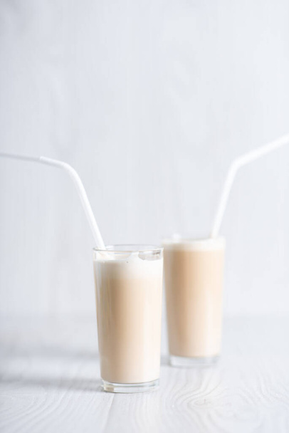 Trendy breakfast. Dalgon coffee. Milkshake with instant coffee and sugar, whipped to a thick foam in glasses with a straw on a light background. - Foto, Imagem