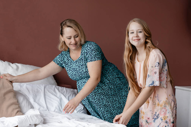 Daughter and mom make a bed in the room.  A happy family. Spend time with each other. The concept of care for the disabled. Family story. Mothers Day. Coppy Space. Toning. - 写真・画像