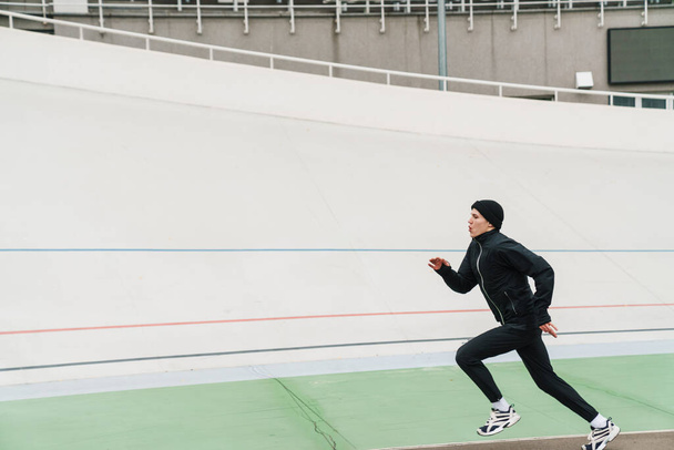 Junger selbstbewusster Sportler läuft im Stadion - Foto, Bild