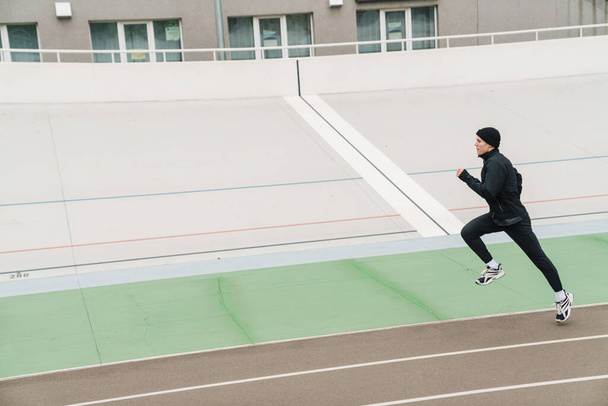 Young confident sporty man running at the stadium - Fotoğraf, Görsel