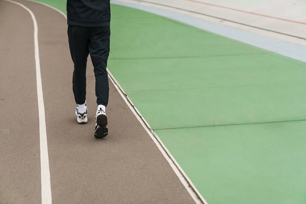 Athletic sportsman running while working out at stadium outdoors - Valokuva, kuva
