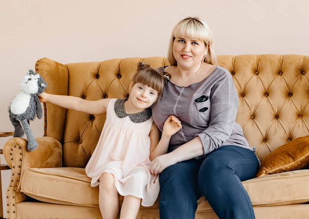 Mom and daughter are sitting on a brown sofa with a plush toy. Mothers Day. Coppy Space. Toning. - Fotoğraf, Görsel