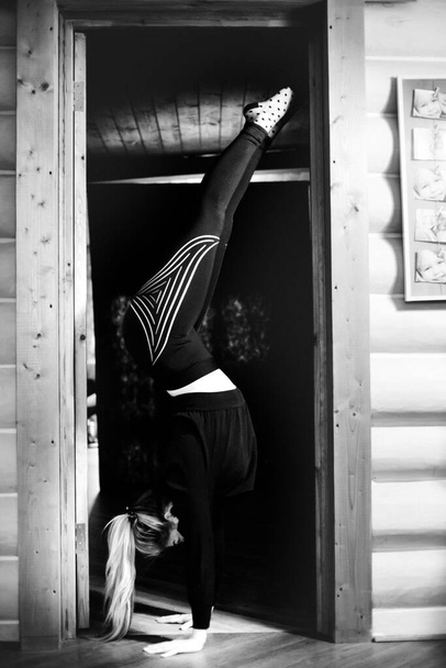 Photo of a gymnast standing in the doorway on her arms. Gymnastics and sports concept. - Фото, зображення