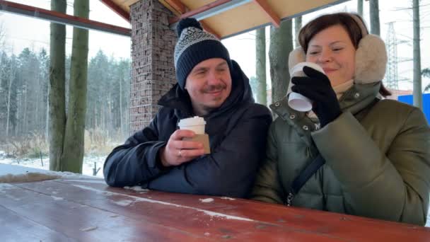 Jeune couple boit du café ensemble en plein air à l'hiver. Couple romantique. Mouvement lent. - Séquence, vidéo