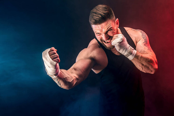 Sportsman muay thai boxer fighting on black background with smoke. Sport concept - Zdjęcie, obraz