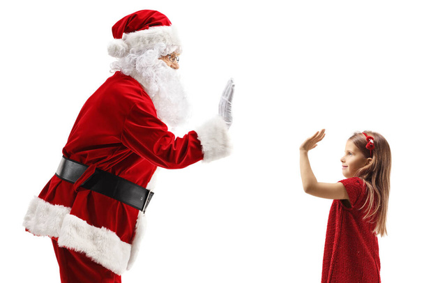 Der Weihnachtsmann gestikuliert mit einem kleinen Mädchen in einem roten Kleid auf weißem Hintergrund - Foto, Bild