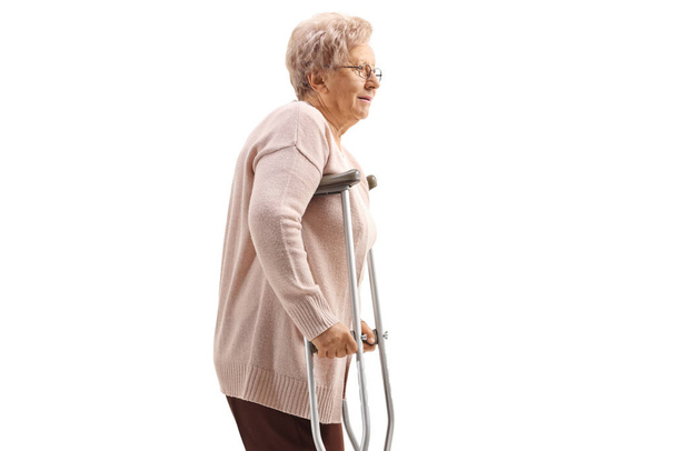 Elderly woman with crutches isolated on white background - 写真・画像