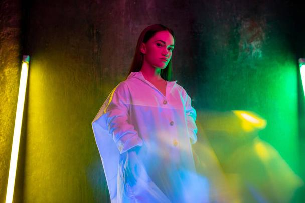 Caucasian female inclusive model posing on studio background in neon light - 写真・画像