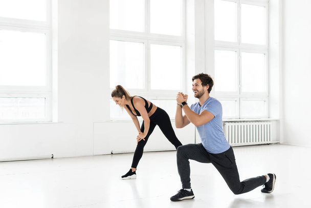 Fitness man and woman during workout with in the gym. Lunges exercise for glutes and hips muscles. - Fotoğraf, Görsel
