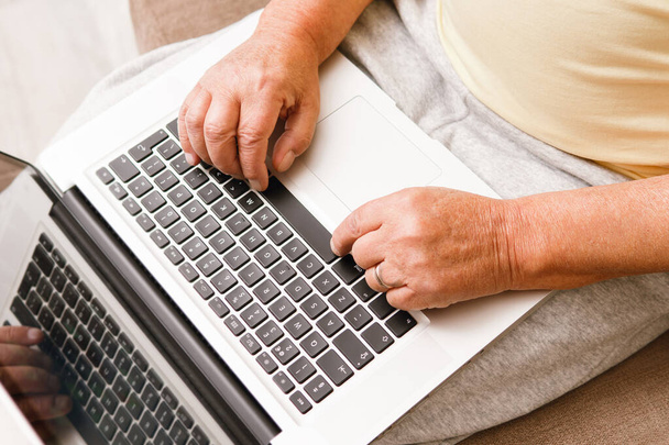 Close-up of elderly man' hands. Senior man is using laptop computer at home - Fotó, kép