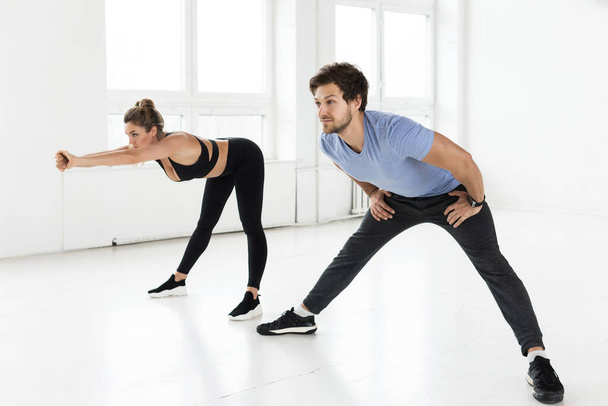 Fitness man and woman during workout with in the gym.  Lower back warm-up. - Foto, afbeelding