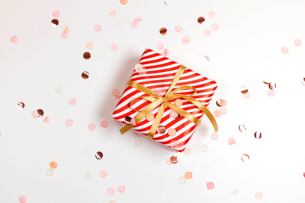 Bonne année composition horizontale. Boîte cadeau design rayé de Noël, arc en or, lumière scintillante sur fond blanc avec espace de copie. Couché plat, vue du dessus - Photo, image