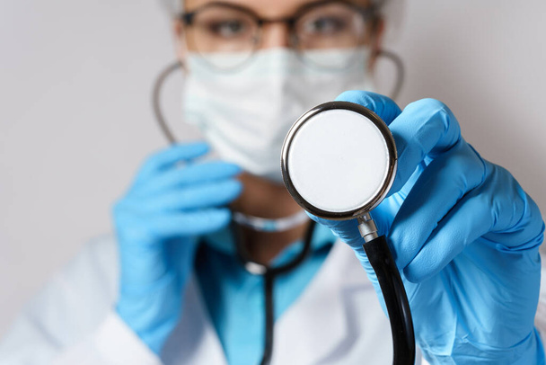 Young female doctor pulmonologist with a stethoscope on gray background - Zdjęcie, obraz