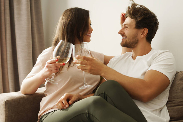 Young and happy couple drinking wine and relaxing at home - Zdjęcie, obraz