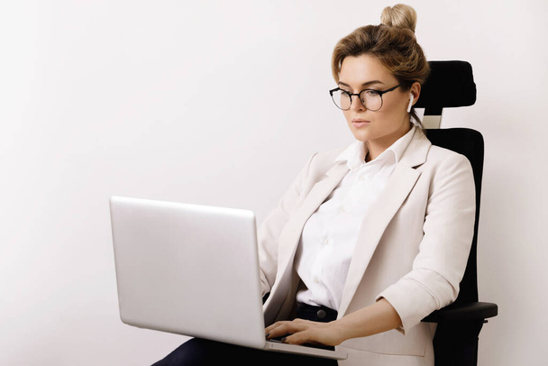 Young businesswoman sitting on the office chair and using laptop pc - Foto, immagini