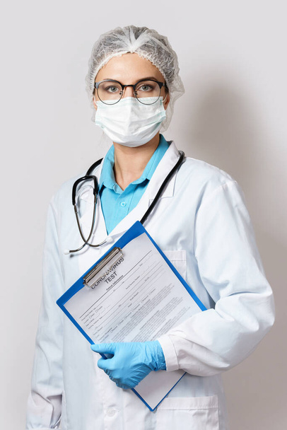 Young female doctor holding folder with a coronavirus test form - 写真・画像