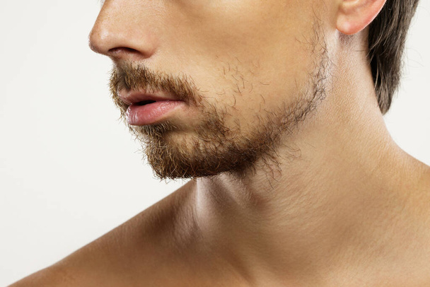 Крупним планом ненадійне чоловіче обличчя з непокритою бородою
 - Фото, зображення