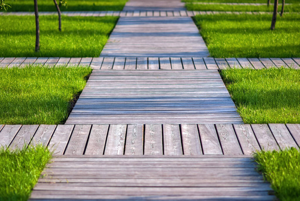 Wooden garden paths - walkways of natural wood planks among green grass and trees - Фото, изображение