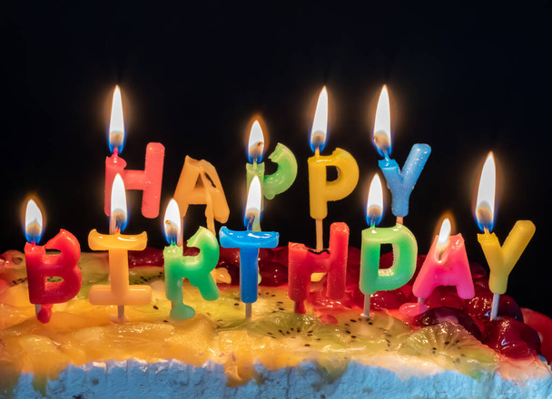 Verlichte kaarsen in de vorm van brieven een gelukkige verjaardag. - Foto, afbeelding