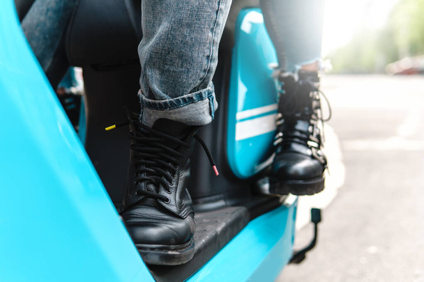 Couple riding motorcycle. Close-up of a scooter body and legs wearing boots - 写真・画像