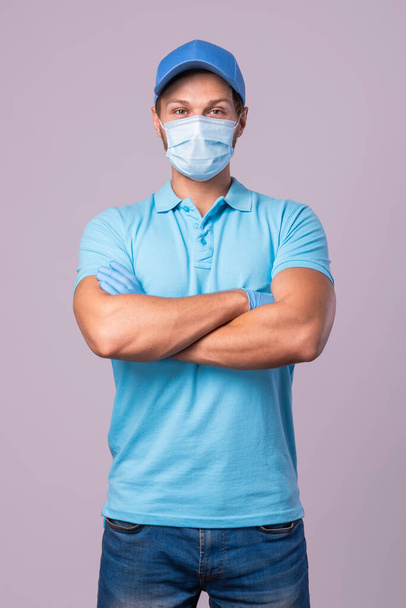 Young man wearing blue uniform with a prevention mask and gloves isolated on gray background - Φωτογραφία, εικόνα