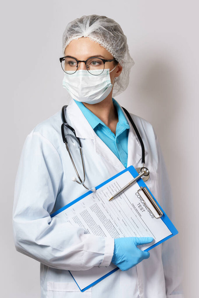 Young female doctor holding folder with a coronavirus test form - Fotoğraf, Görsel