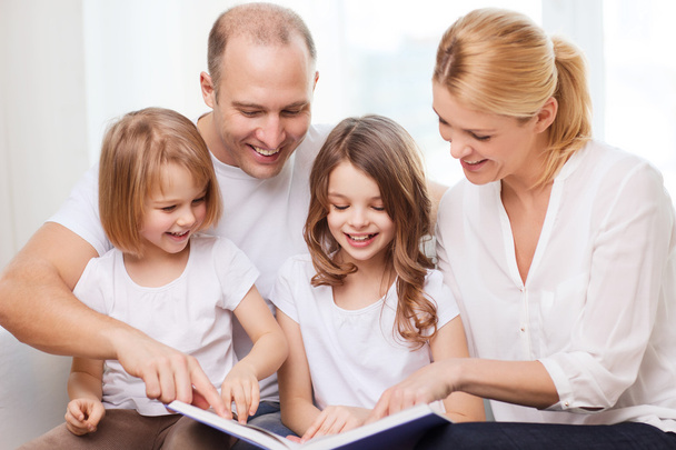 Smiling family and two little girls with book - Foto, Imagen