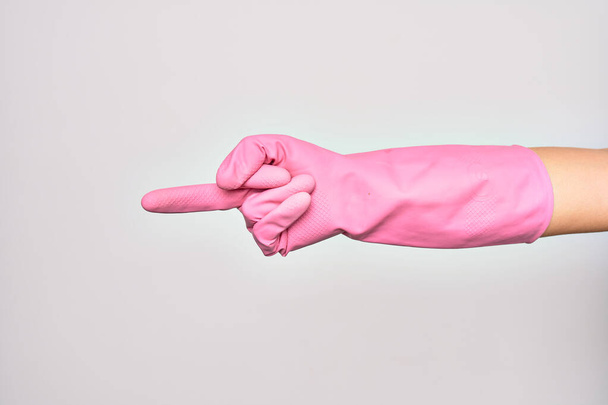 Hand of caucasian young woman wearing pink cleaning glove. Showing middle finger doing fuck you sign over isolated white background - Foto, Imagen