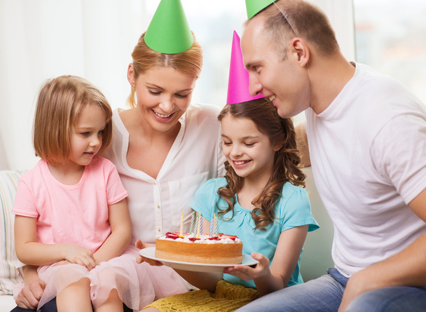 ケーキと帽子で 2 人の子供を持つ家族の笑顔 - 写真・画像