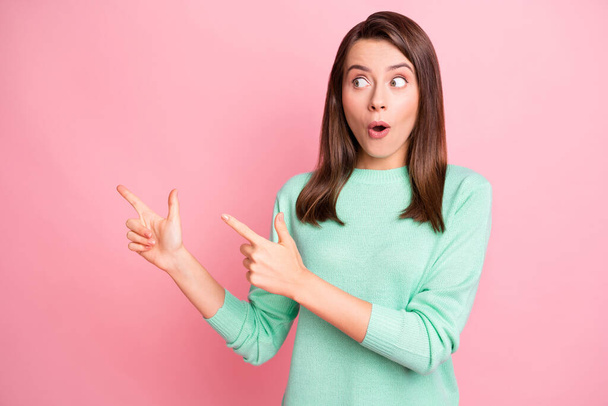Photo of amazed lady shocked look indicate fingers empty space wear teal sweater isolated pink color background - Photo, image
