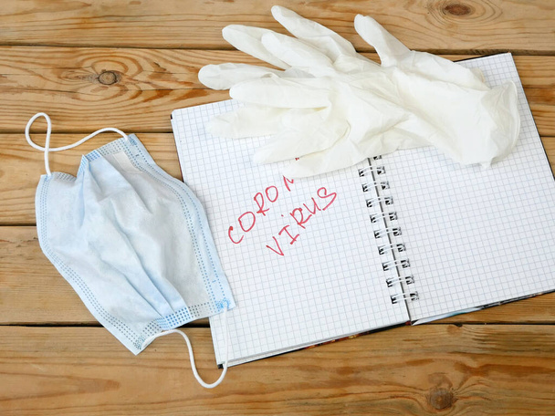 medical mask, gloves, notepad and pen on wooden background, health care concept and prevent the spread of pandemic., closeup - Foto, afbeelding